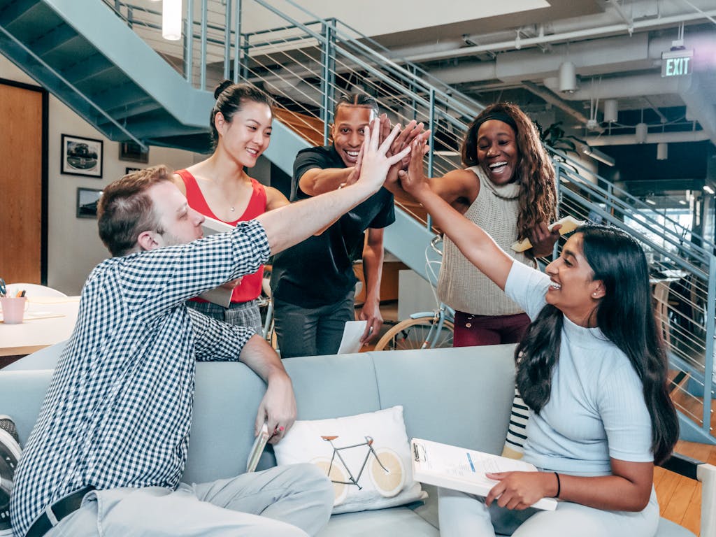 A multicultural office team high-fiving and celebrating a successful content marketing collaboration.