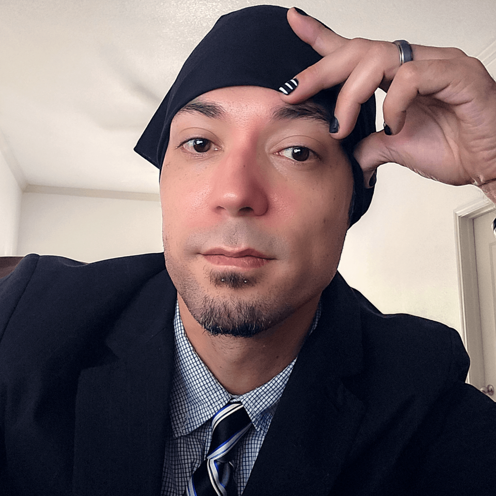 A headshot of a man in a black bandana and suit.