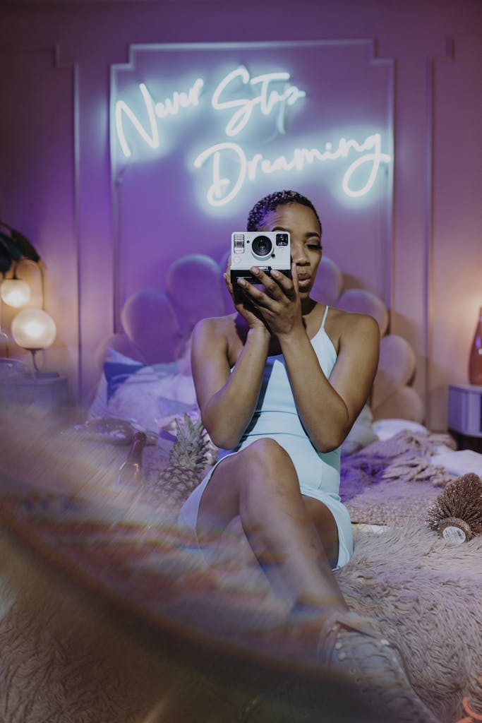 Woman in stylish room with neon sign and retro camera, embodying dream and creativity for digital marketing.