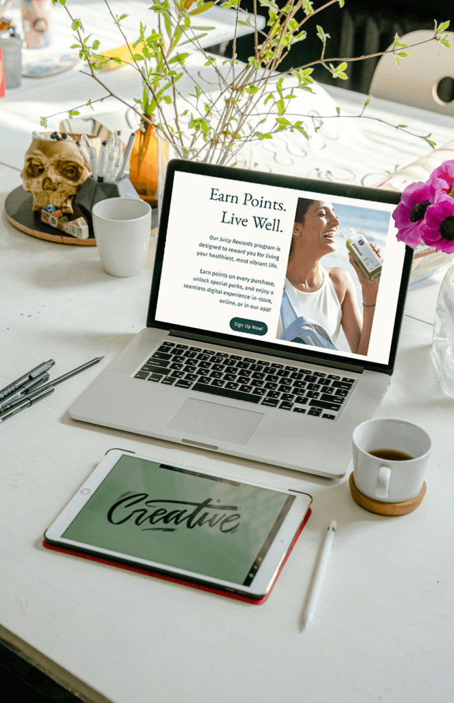 Desktop view of the Juicy Rewards website displayed on a laptop, showcasing the full landing page layout with headline, product image, and rewards sign-up section.