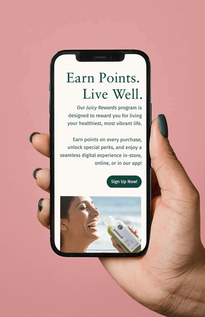 A mobile webpage mockup is displayed on a cell phone held by a hand over a pink background.